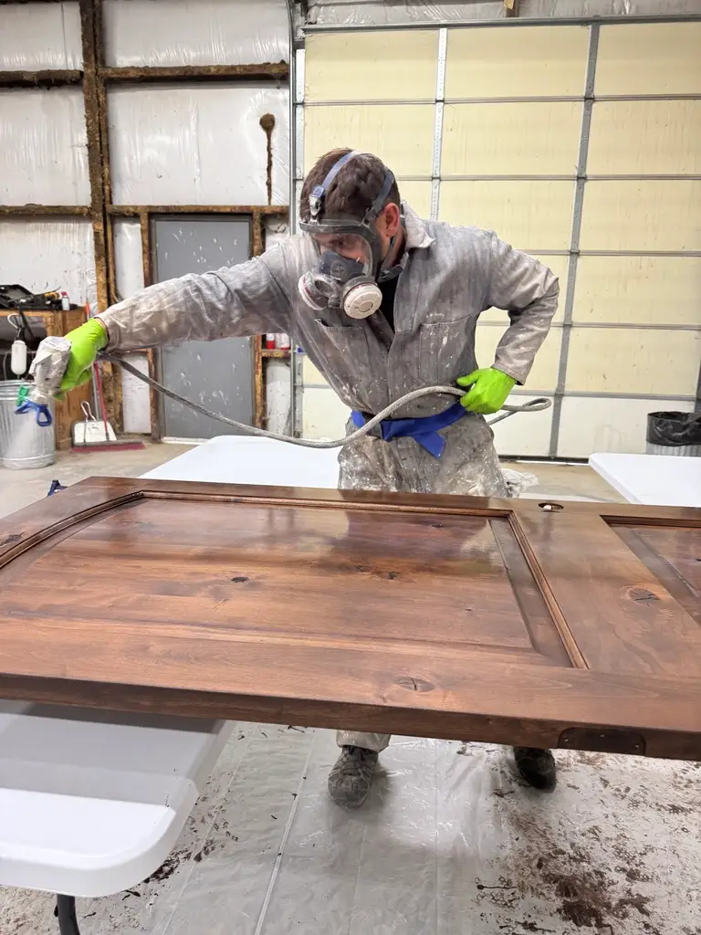 Zenith Paint and Finish applying stain to a custom wood door for a smooth durable finish