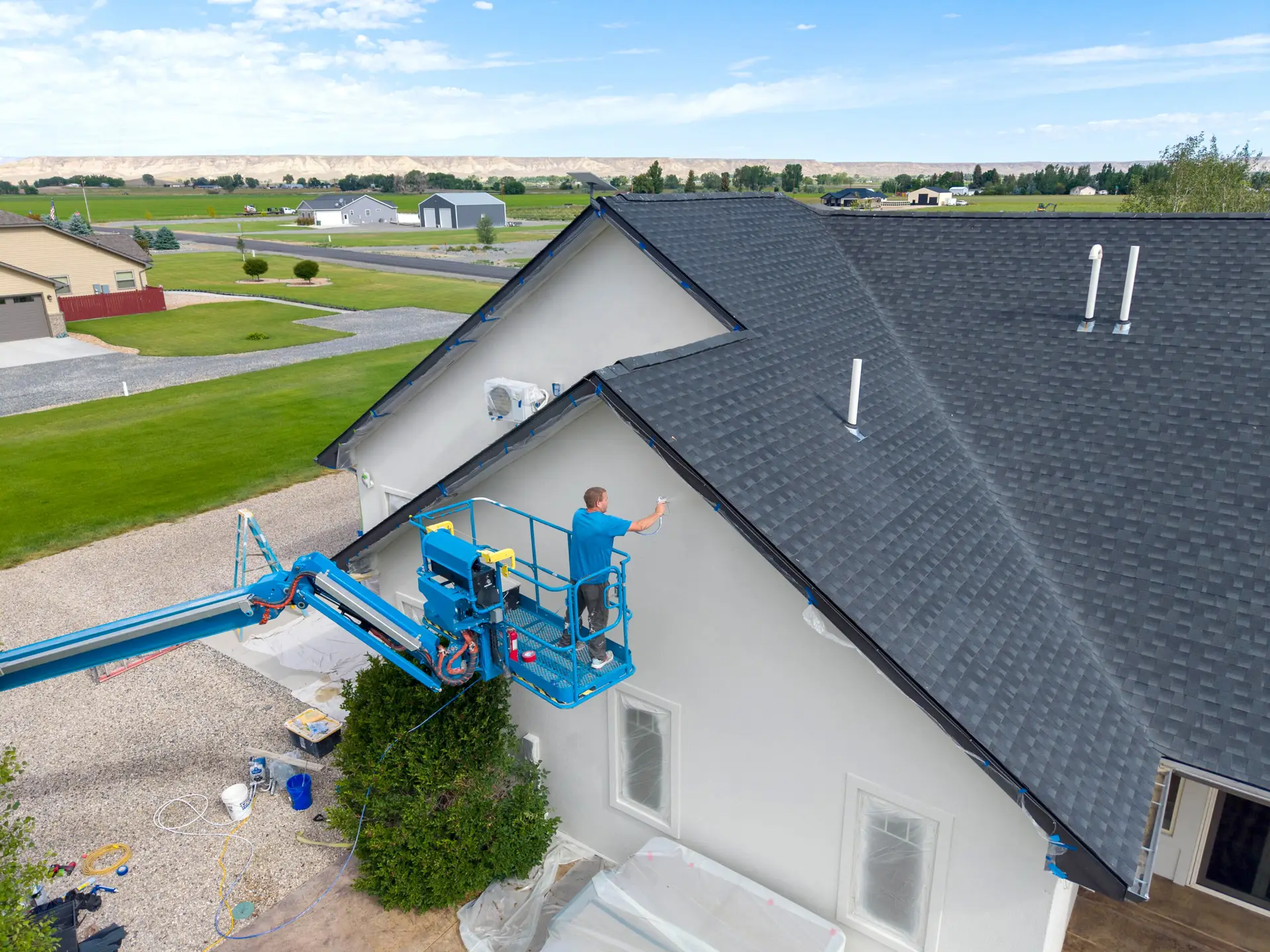 Professional painter spray painting residential stucco exterior in Wyoming