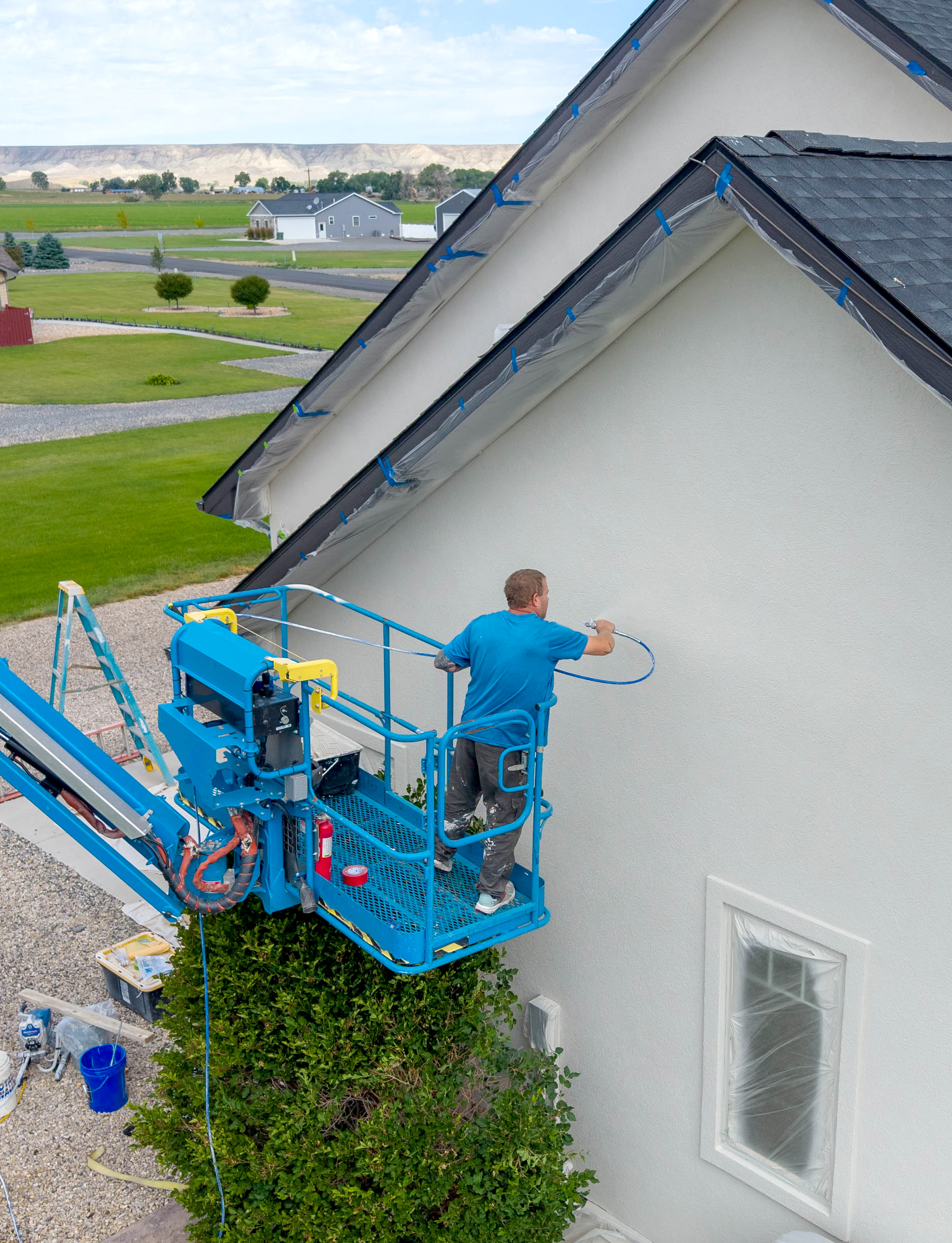 House exterior being professionally spray painted with boom lift in Wyoming