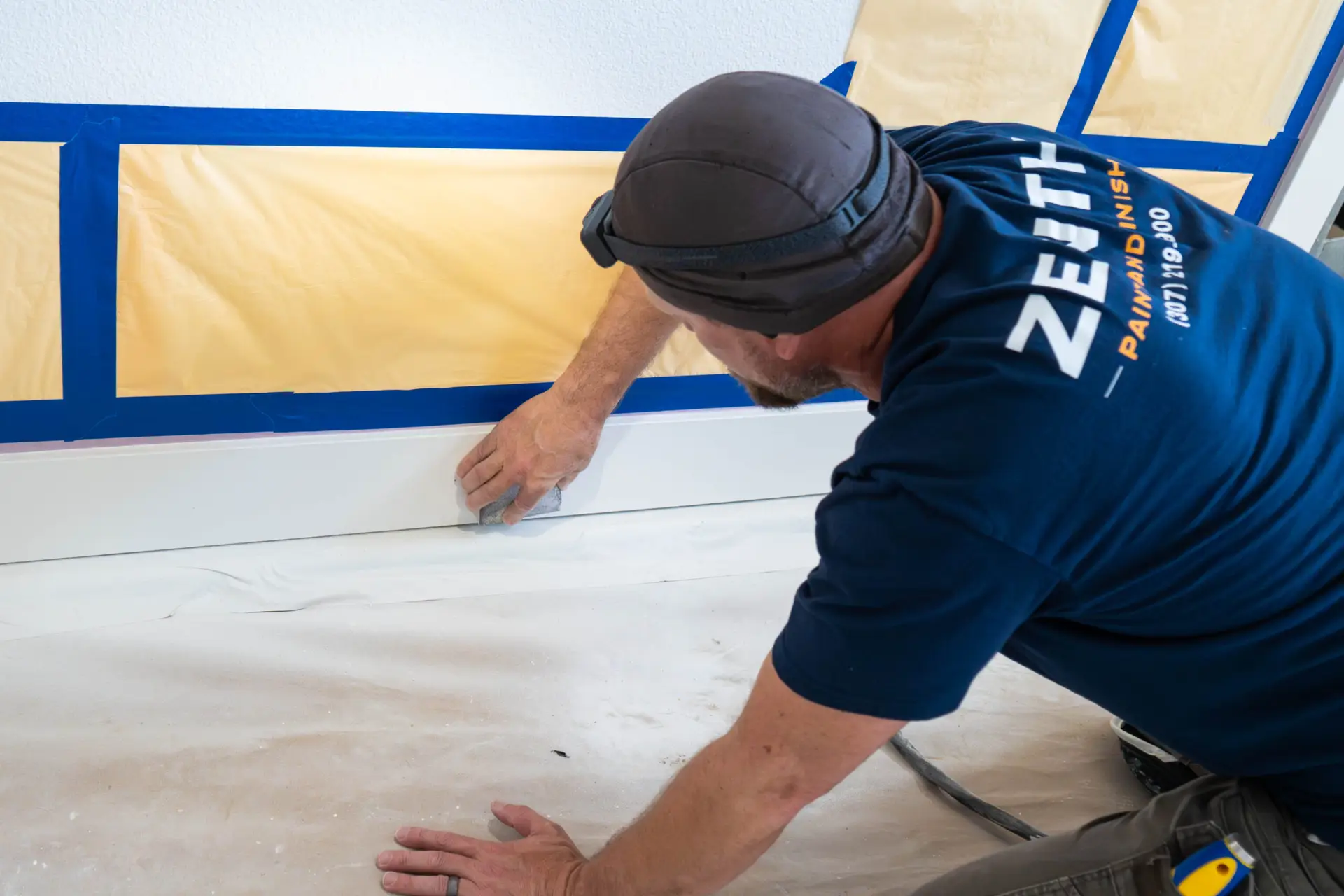 Precision masking of baseboards before spraying by the Zenith Paint and Finish team