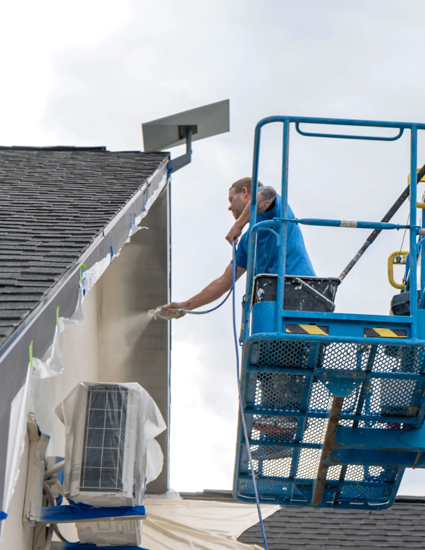 Professional painter spray painting exterior home from boom lift in Wyoming