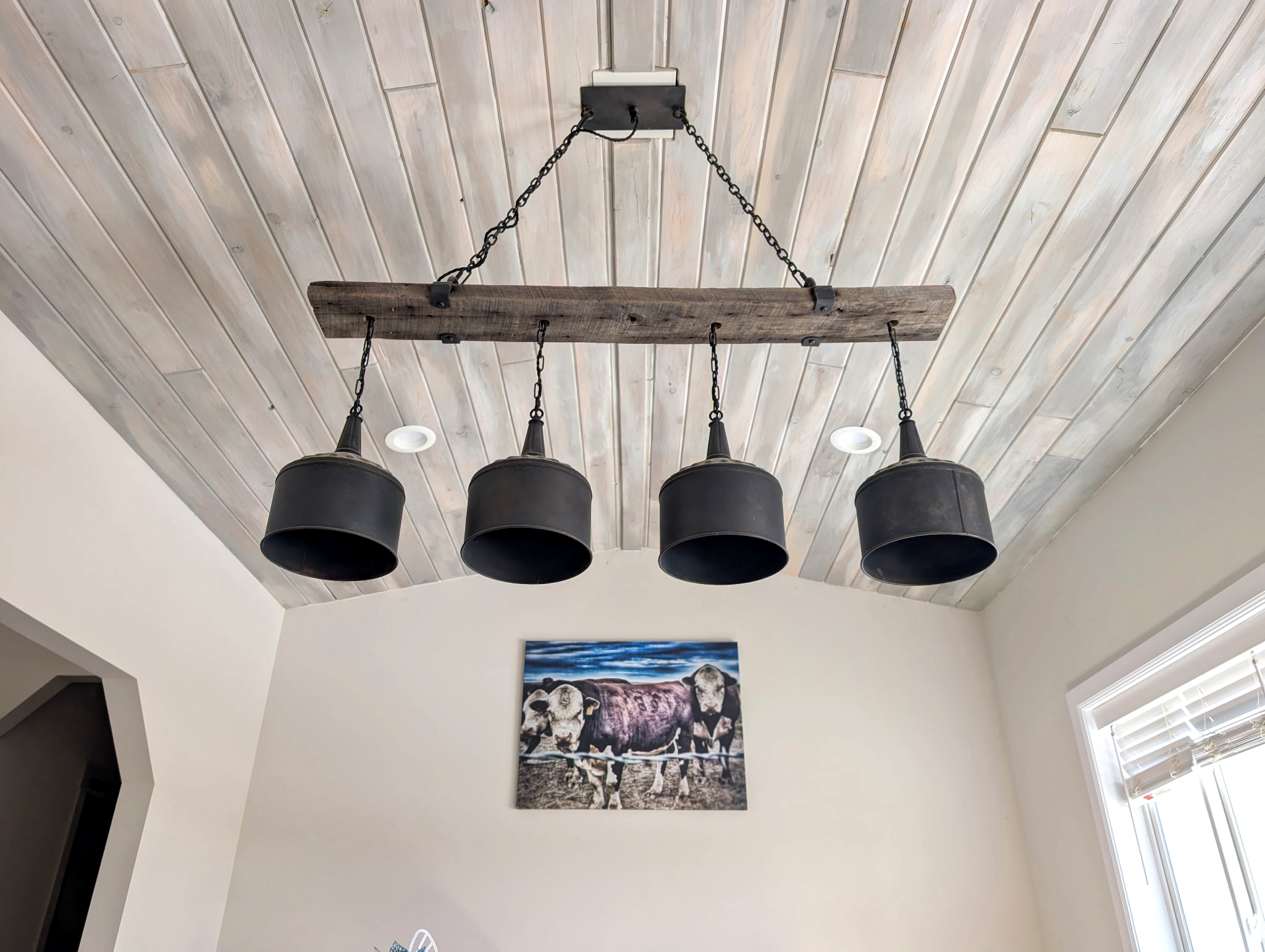 A light stained wood ceiling brightens the room while enhancing its architectural detail, expertly finished by Zenith Paint and Finish to complement the home's modern rustic design.